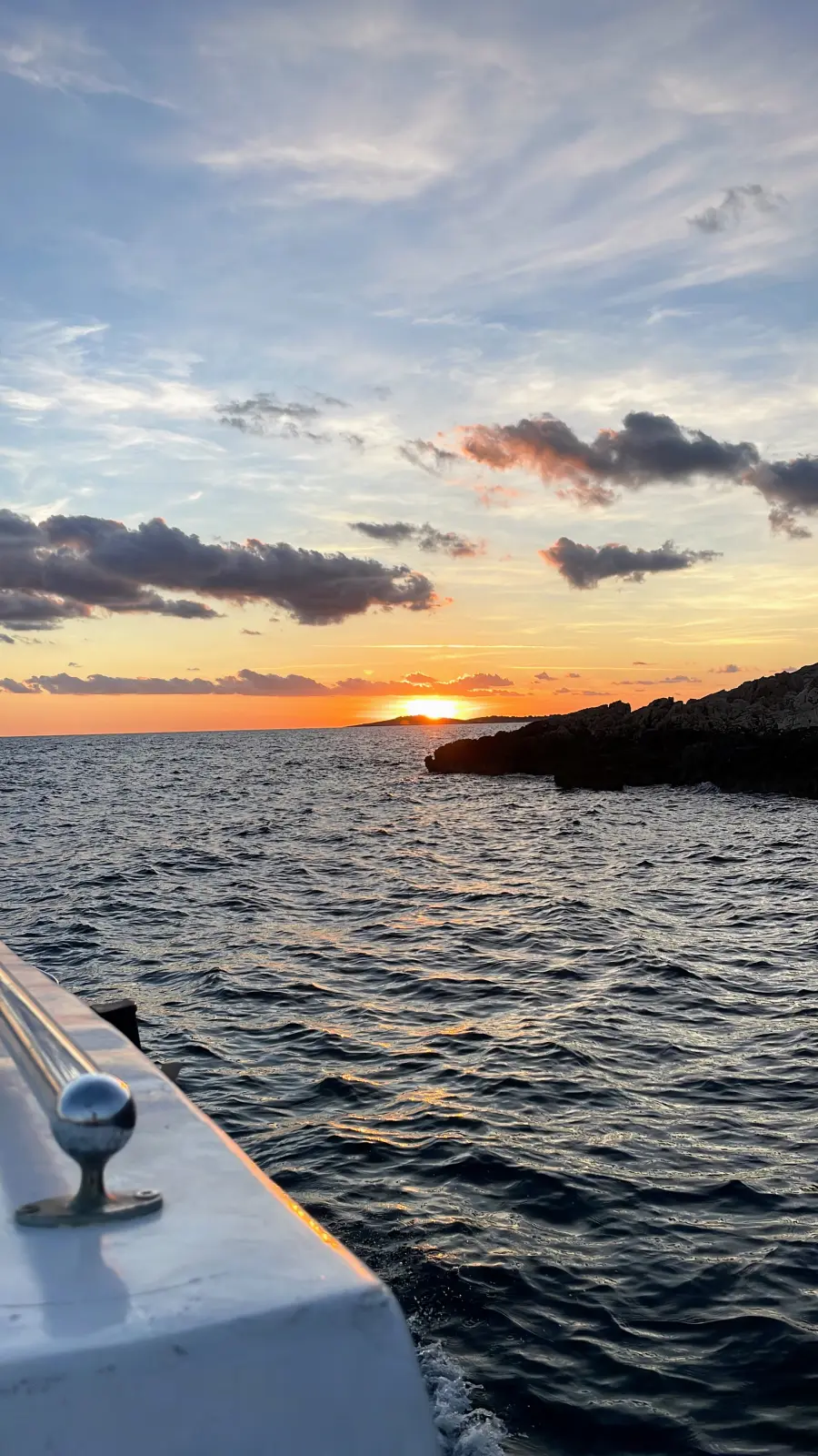 Sunset over the ocean, viewed from a small boat