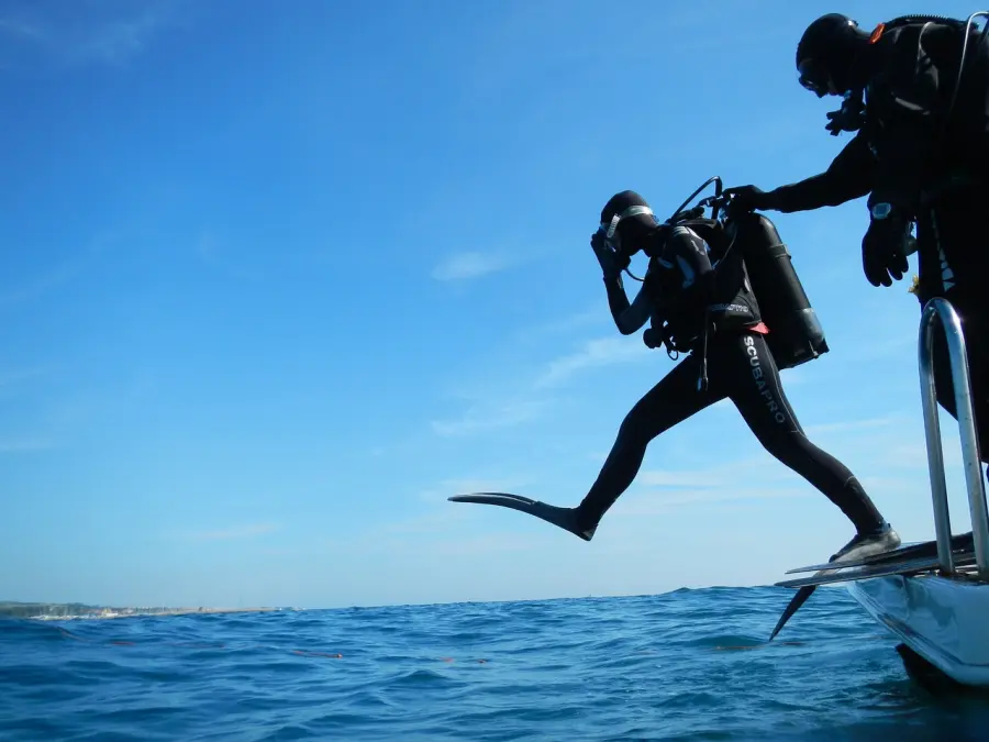 Scuba divers in wetsuits and gear leaping into the clear blue waters off the coast of Murter Island for an underwater adventure.