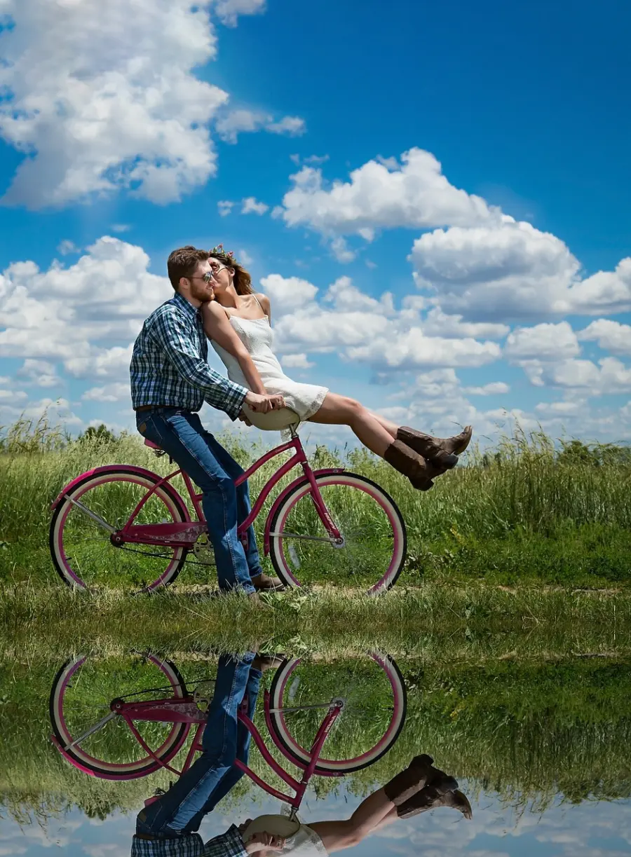 A couple cycling by a pond, enjoying a leisurely ride together on a sunny day.