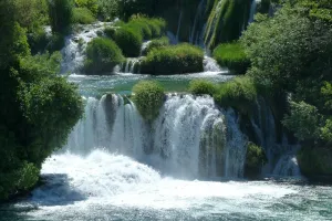 Niz slapov med bujnim zelenjem v mirnem naravnem okolju.