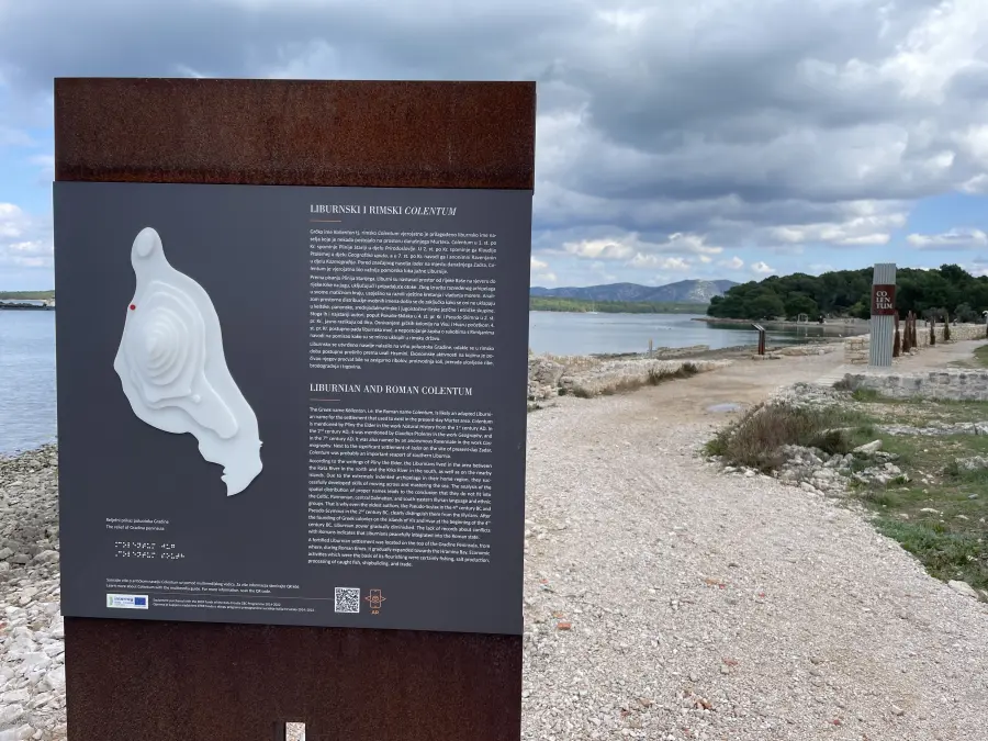 Informative Tafel über das liburnische und römische Colentum mit einer Reliefkarte entlang eines Küstenwegs auf der Insel Murter mit Blick auf das Meer und die Hügel in der Ferne