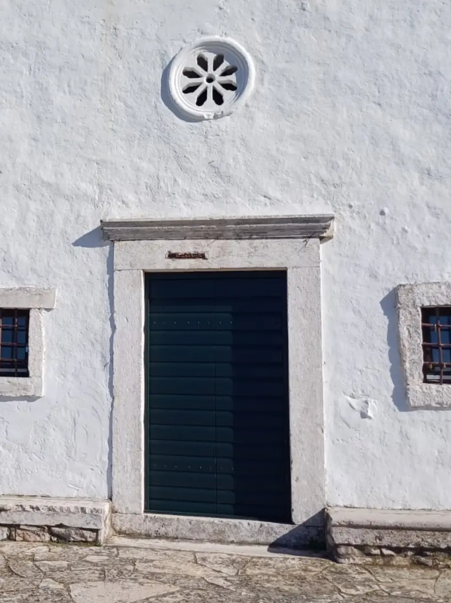 White building with a green door and two windows.
