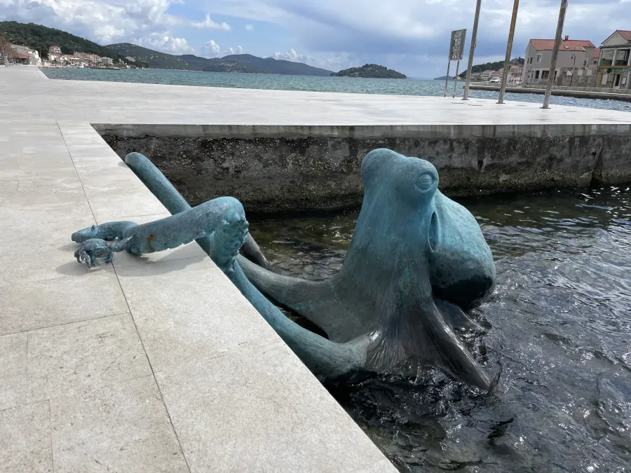 Statue of an octopus leaning against a pier.